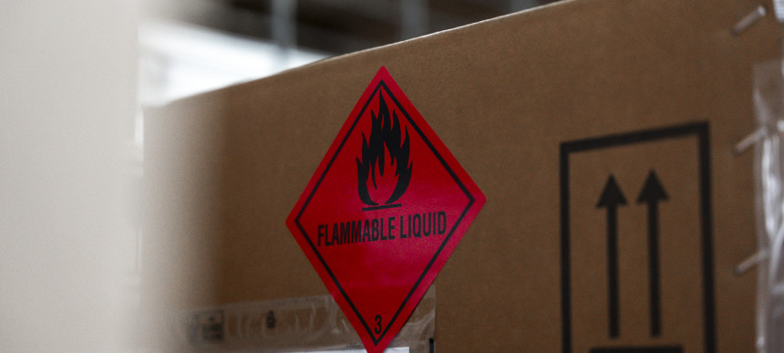 Nahaufnahme eines Kartons mit einem roten Gefahrensymbol für entzündbare Flüssigkeiten und einem schwarzen Symbol mit zwei nach oben zeigenden Pfeilen