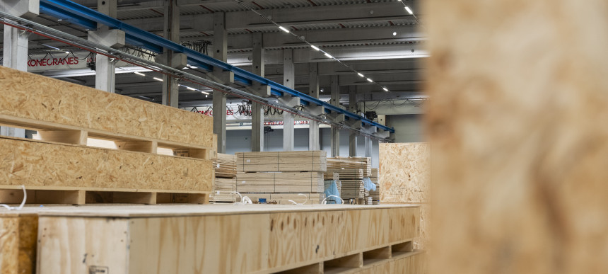 Große Lagerhalle mit gestapelten Holzkisten und sichtbaren Stahlträgern an der Decke