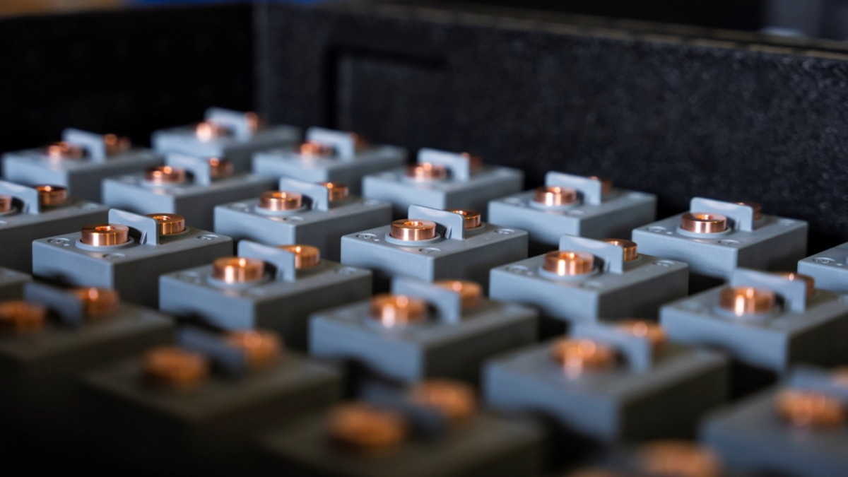 Nahaufnahme eines Gitters aus grauen Batteriezellen mit markanten Kupferanschlüssen.