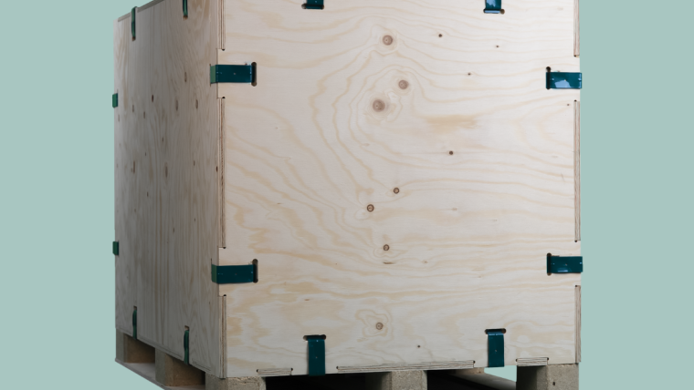 AXXUM kliXXkiste: Eine große Holzkiste mit grünen Metallklammern an den Ecken steht auf einer Palette.