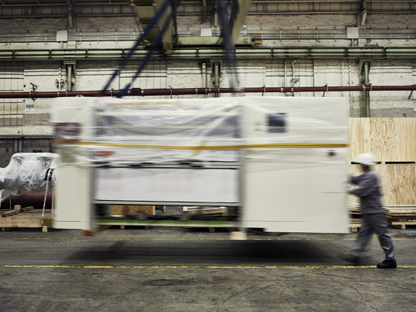 Eine große Maschine wird mit Hilfe eines Kranes von einer Person bewegt