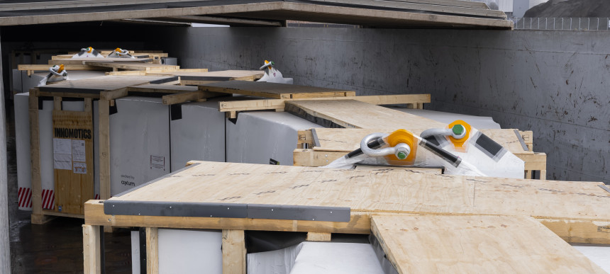 Mehrere große, mit Holzplatten abgedeckte Container in einem Schiff.