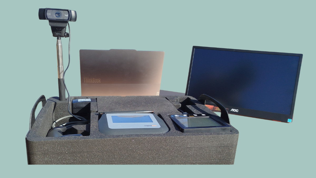 Tragbare Abstimmungsvorrichtung mit einer Webcam auf einem Ständer, einem Laptop, einem Monitor und einem in einen Schaumstoffkoffer eingebauten Gerät.